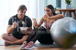 After workout snacks. Full length shot of an athletic young couple enjoying some healthy snacks after their workout at home.