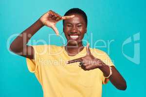 Change your perspective change your outcome. Studio shot of a confident young woman making a finger frame of her face against a turquoise background.