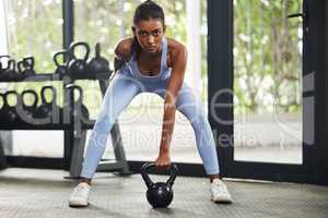 The real workout starts when you want to stop. Shot of a young woman working out with a kettle bell at the gym.