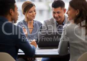 Youre getting the hang of this. Shot of two young businesspeople sitting together in the office and having a discussion while using a laptop.