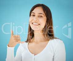 Call me. Studio shot of a young woman holding her hand out and showing the hang ten sign.