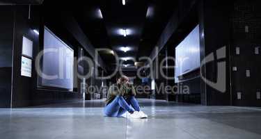 Sometimes it all just gets too much. Full length shot of a young woman looking depressed while sitting on the floor of a train station terminal.