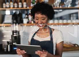 Taking advantage of technological tools to boost sales. Shot of a young woman using a digital tablet while working in a cafe.