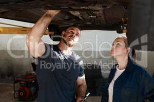 Top notch service is our main automotive. Shot of two mechanics working together under a lifted car.