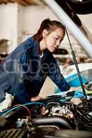 Its my job to solve challenging problems. Shot of a female mechanic working on a car in an auto repair shop.