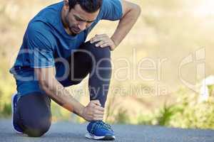 I need better running shoes. Shot of a handsome young man kneeling and suffering from a sprained ankle during his outdoor workout.