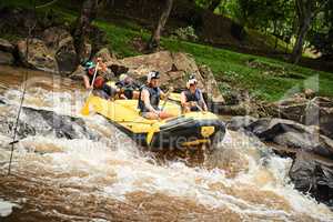 Navigating some tricky waters. High angle shot of a group of young friends white water rafting.