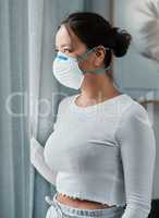 This pandemic changed my outlook on life. Shot of a young woman wearing a mask while looking out a window at home.