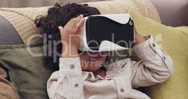 Glued to the screen. Shot of a little boy watching movies together through virtual reality headsets at home.