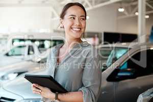 Get ready for the smoothest ride of your life. Shot of a woman using her digital tablet in a car dealership.