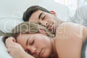 No need to rush today. Shot of a relaxed young couple sleeping in bed together at home.