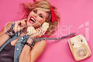 Everyone had so much fun in the 80s. Studio shot of a young woman holding a telephone while wearing 80s clothing.