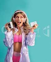 The polarizing era in fashion is back in a big way. Studio shot of a young woman holding a cassette player while dressed in 80s clothing.