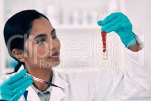 Lets see how this blood will react with this liquid. Cropped shot of an attractive young female scientist inspecting a blood sample in a test tube while working in a laboratory.