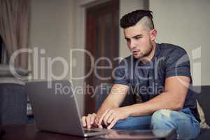 You dont get ahead by taking weekends off. Shot of a driven young man using his laptop to work from home.