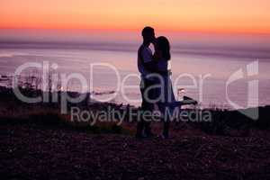 Madly in love. Full length shot of an affectionate young couple silhouetted at sunset.