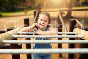 The park is her favourite place to enjoy endless fun. Portrait of a little girl playing on the jungle gym at the park.