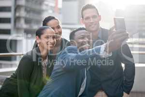 Getting the team spirit going. Shot of a group of businesspeople taking a selfie against a city background.