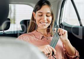 Safety gives me a smile. Shot of a young woman fastening her seatbelt in a car.