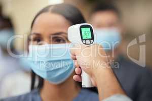 Nice and healthy. Cropped shot of an attractive young businesswoman wearing a mask and having her temperature taken while standing at the head of a queue in her office.