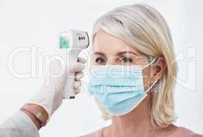 A normal temperature gets you through the door. Shot of a woman wearing a mask while having a temperature taken.