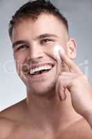 Take your skin back to yesterday, every day. Cropped closeup shot of an attractive young man applying moisturiser to his face against a grey background.