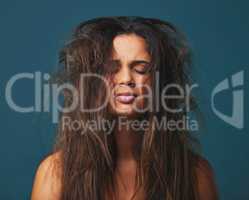 Pain you hold makes you worth your weight in gold. Studio shot of a beautiful young woman with messy hair posing against a blue background.