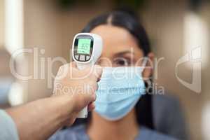 No sign of fever here. Cropped shot of an attractive young businesswoman wearing a mask and having her temperature taken while standing at the head of a queue in her office.