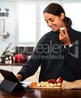 Give me all the starch. Shot of a young woman chopping vegetables while watching a video recipe.