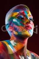 The world is my canvas and I create my reality. Studio shot of a young woman posing with multi-coloured paint on her face.