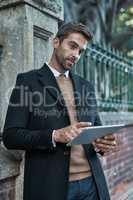 Doing his business on the move. Cropped shot of a handsome businessman using his tablet while about town.