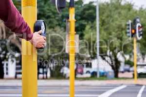 Waiting to walk. Shot of a mans hand pressing the crossing button at an intersection.