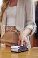 Spending some hard earned cash. Shot of a woman using her bank card to pay for a purchase in a store.