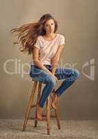 She has fire in her soul. Studio shot of a beautiful young woman sitting on a stool against a plain background.