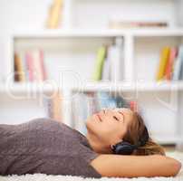 Shes as carefree as can be. Shot of a young woman listening to music while relaxing at home.