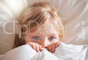 I dont feel good at all. Shot of a little girl feeling ill in bed at home and covering with a blanket.