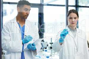 Doing the maths to prove their theory. Shot of two scientists solving equations on a glass screen in a laboratory.