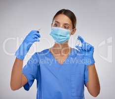 Keep others safe by vaccinating. Shot of a young female nurse holding a needle and vial of vaccination fluid against a studio background.