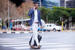 Success is walking from failure to victory. Shot of a young businessman walking and using a phone in the city.