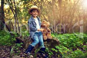Theres no better companion in the woods. Shot of a little boy sitting in the forest with his teddy bear.