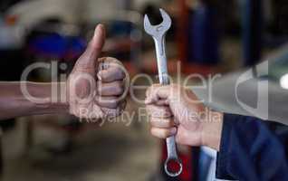 Thumbs up for maintenance. Closeup shot of one mechanic holding a spanner and another giving thumbs up in their workshop.