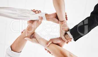 None of us is as strong as all of us. Low angle shot of a group of businesspeople holding one anothers wrists in a circular formation.