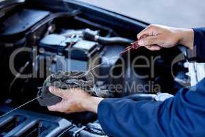 Checking your oil. High angle shot of an unrecognizable male mechanic working on the engine of a car during a service.