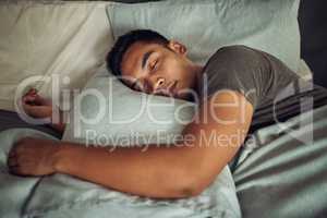 Nothing soothes the soul like a deep sleep. Shot of a young man sleeping peacefully in bed at home.
