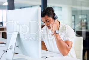 I can hear your clearly, sir. Shot of a handsome young businessman sitting alone in his office and wearing a headset while using his computer.