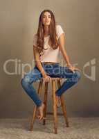 I was not made to be subtle. Studio shot of a beautiful young woman sitting on a stool against a plain background.