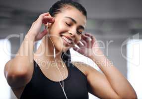 Motivational music makes all the difference. Shot of a fit young woman using earphones at the gym.