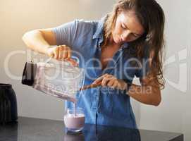 Failing to plan is planning to fail. Shot of a young female preparing a smoothy at home.