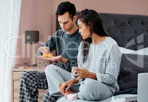 Teaming up to take down the flu. Shot of a young couple taking medication while recovering from an illness in bed at home.