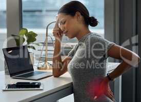 I really need to lie down. Shot of a young businesswoman experiencing a headache and back pain in her office.